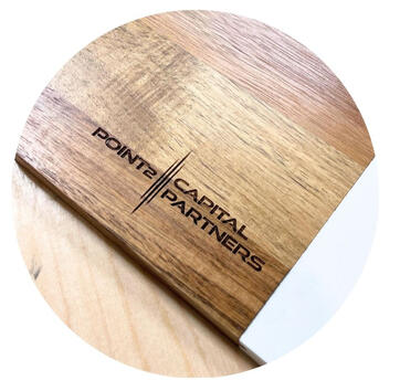 Close-up of a corporate branding project featuring a custom laser-engraved wood and marble serving board. Part of a 210-piece bulk order for Point2 Capital Partners, showcasing consistent, high-contrast wood engraving for corporate gifts.